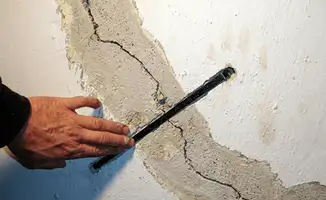 A wall with a large crack is being inspected by a professional in Long Beach, CA